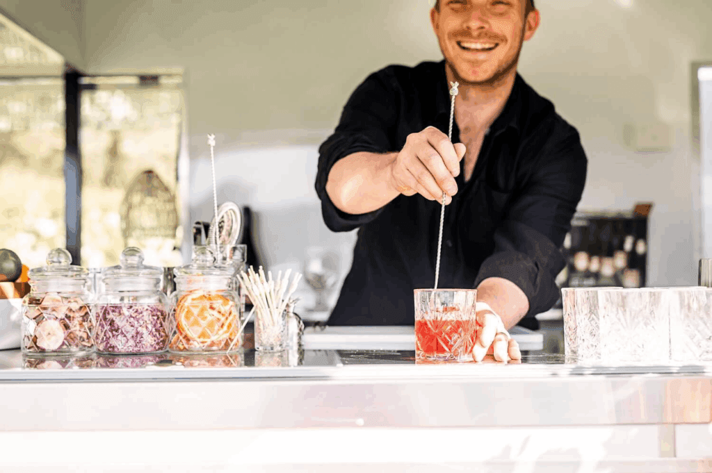 Bartender mixing and serving drinks inside the mobile bar.