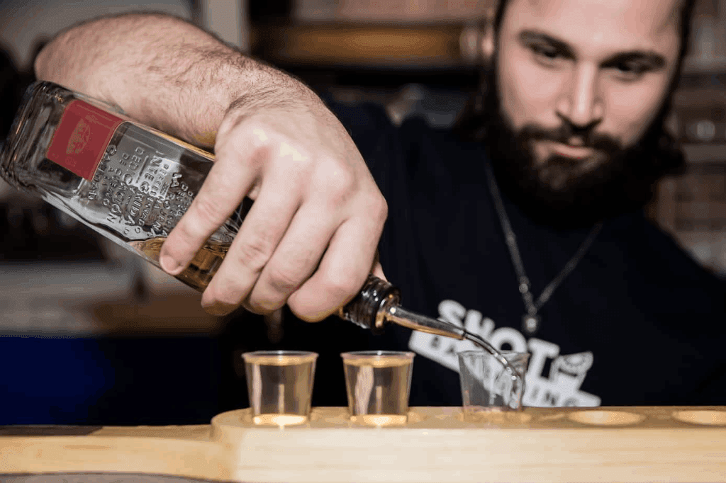 Bartender pouring drinks into a shot glass.