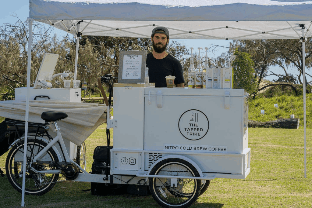 Barista of the Tapped Trike mobile bar serving drinks in an event.